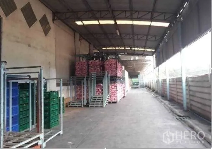 Factory for sale in Khlong Luang, Pathum Thani - Covered warehouse aisle with high roof, ventilation panels and stacks of crates and goods.