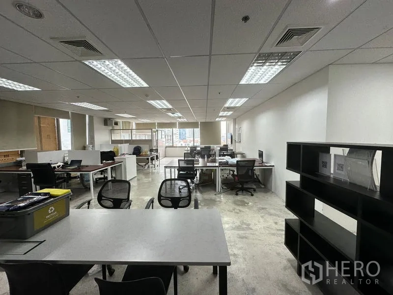 Office Space for rent in Khlong Toei, Bangkok - Spacious open office with multiple desks, shelving and suspended ceiling lights.