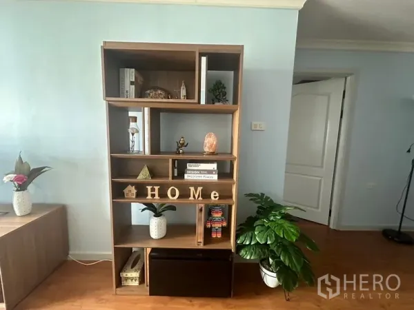 Condominium for rent in Watthana, Bangkok - Modern open shelving with decor accents and indoor plants in the living area.
