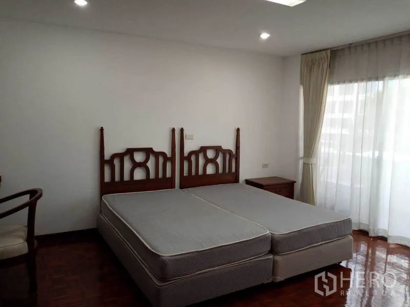 คอนโด ให้เช่าในWatthana, Bangkok - ห้องนอนที่สอง เตียงคู่ หัวเตียงไม้ และหน้าต่างบานใหญ่พร้อมม่านโปร่ง