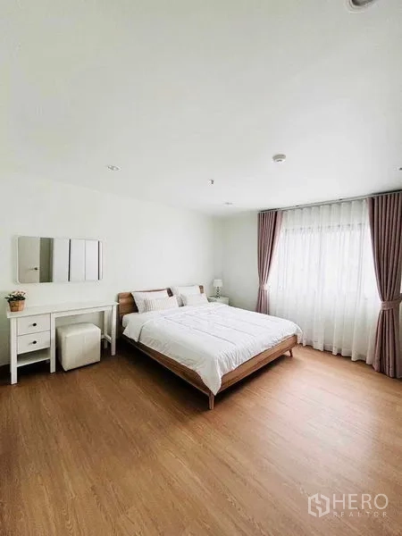 Condominium for rent in Watthana, Bangkok - Master bedroom with king bed, dressing table and a wide window with curtains.