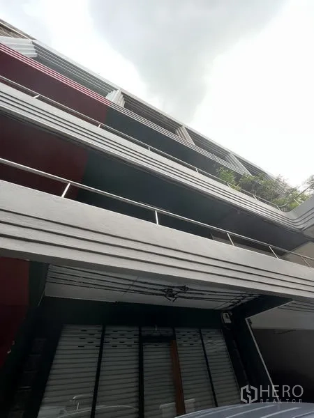 店屋 出租在Khlong Toei, Bangkok - 多层店屋外立面，带阳台与一层卷帘门店面。