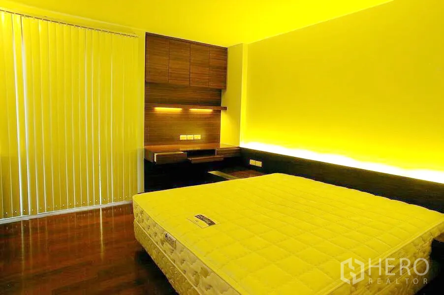 Condominium for rent in Watthana, Bangkok - Bedroom with built-in desk and shelving, warm backlit headboard, vertical blinds and wooden flooring.