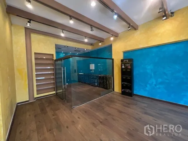 零售空间 出租在Watthana, Bangkok - 销售区带玻璃隔间、展示层架、亮色墙面与聚光照明。