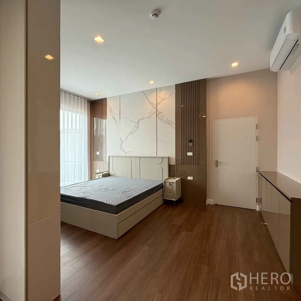 Detached House for rent in Bang Phli, Samut Prakan - Large bedroom with bed, air conditioner, sheer curtains and wood floor.