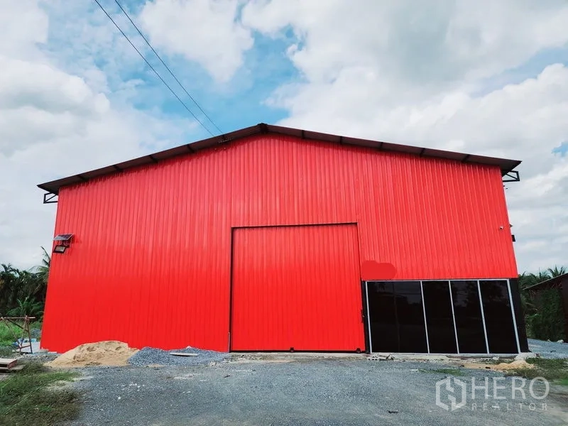 货栈 出租在Sam Phran, Nakhon Pathom - 红色金属外墙正立面，设有滑门与黑色玻璃窗。