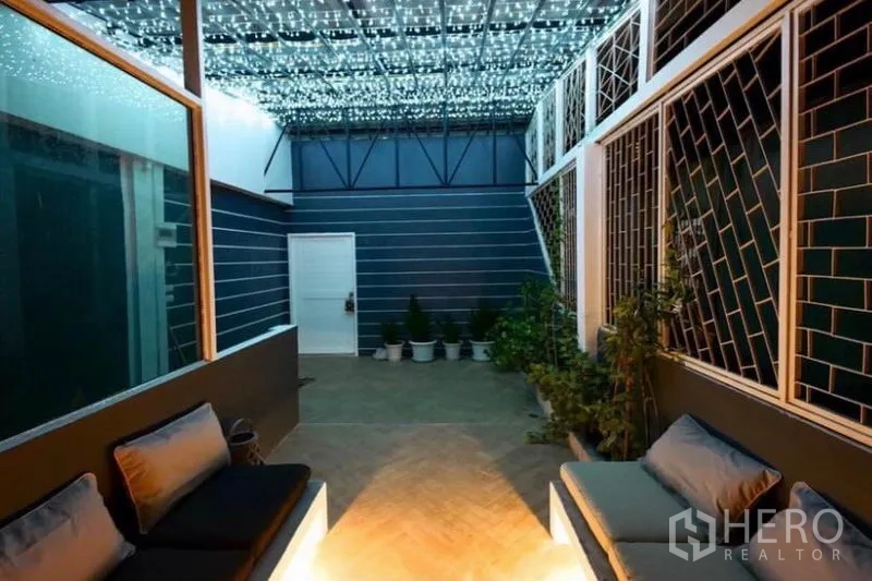 Townhouse for rent in Ratchathewi, Bangkok - Covered patio with string lights, bench seating and potted plants.