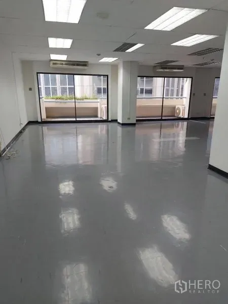 办公空间 出租在Pathum Wan, Bangkok - 开放式办公区，灰色亮面地坪、吊顶照明，玻璃滑门通向阳台。