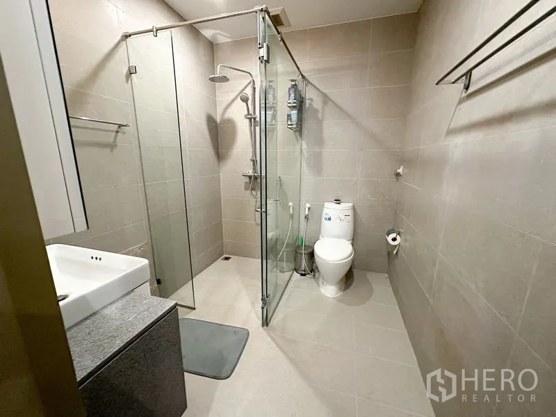 คอนโด ให้เช่าในPathum Wan, Bangkok - ห้องน้ำสมัยใหม่ พร้อมตู้ shower กระจก โถสุขภัณฑ์ และอ่างล้างหน้า โทนกระเบื้องสีเทา