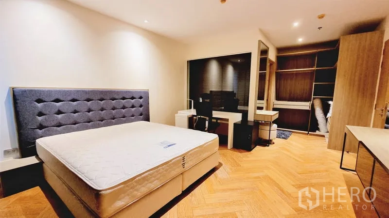 Condominium for sale in Watthana, Bangkok - Master bedroom featuring an upholstered headboard, parquet floors and a walk-in closet.