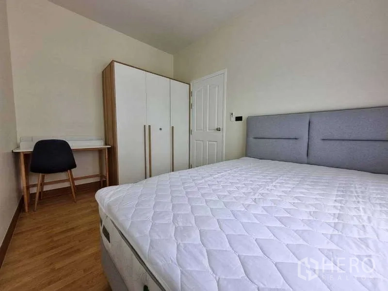 ทาวน์เฮาส์ ให้เช่าในWang Thonglang, Bangkok - ห้องนอนสว่างพร้อมเตียงหัวบุผ้า ตู้เสื้อผ้าสีขาว โต๊ะทำงาน และพื้นลามิเนตไม้