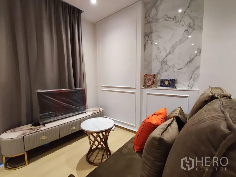 คอนโด ให้เช่าในDin Daeng, Bangkok - มุมนั่งเล่นกะทัดรัด มีชั้นวางทีวี โต๊ะกลางกลม ผ้าม่านทึบ และช่องผนังหินอ่อน