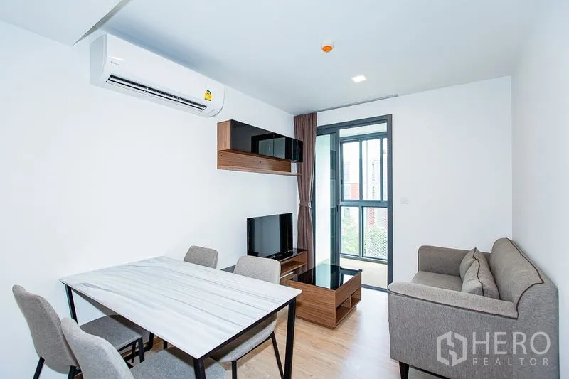 คอนโด ให้เช่าในWatthana, Bangkok - โซนนั่งเล่นมีชั้นวางติดผนัง ชั้นวางทีวี ประตูออกระเบียง และชุดโต๊ะทานอาหาร