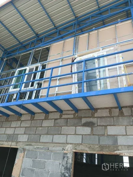 货栈 出租在Pathum Thani - 蓝色钢结构夹层与窗框的近景，位于仍在施工中的仓库立面，Khlong Luang。