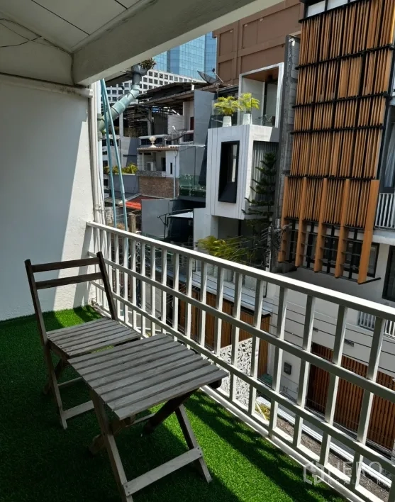 Townhouse for rent in Sathon, Bangkok - Balcony with artificial grass, folding chairs, and urban neighborhood view.