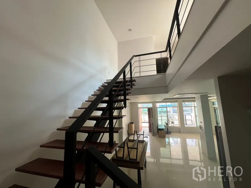 Townhouse for rent in Din Daeng, Bangkok - Double-height stairwell overlooking bright living area with large front windows.