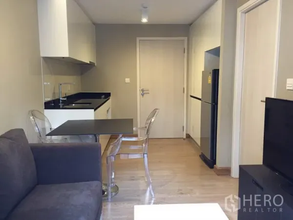 公寓 出租在Watthana, Bangkok - 现代曼谷公寓的客餐厅与一体化小厨房，黑色台面与透明椅。