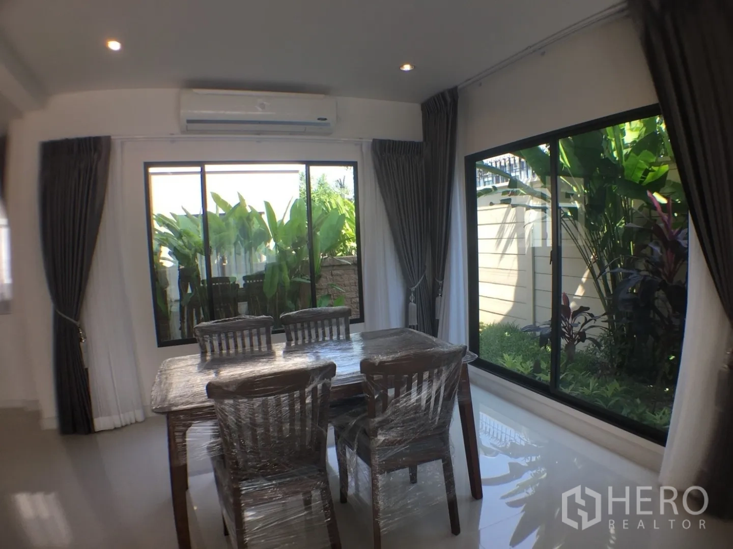 Detached House for rent in Suan Luang, Bangkok - Dining room overlooking a tropical garden through large sliding windows and dark drapes.