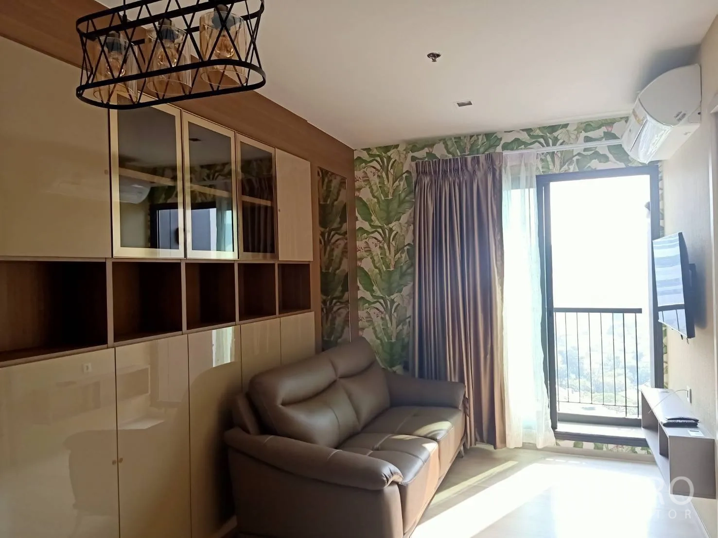 公寓 for rent in Pathum Wan, Bangkok - 明亮客厅配皮沙发、内置柜、壁挂电视与阳台。