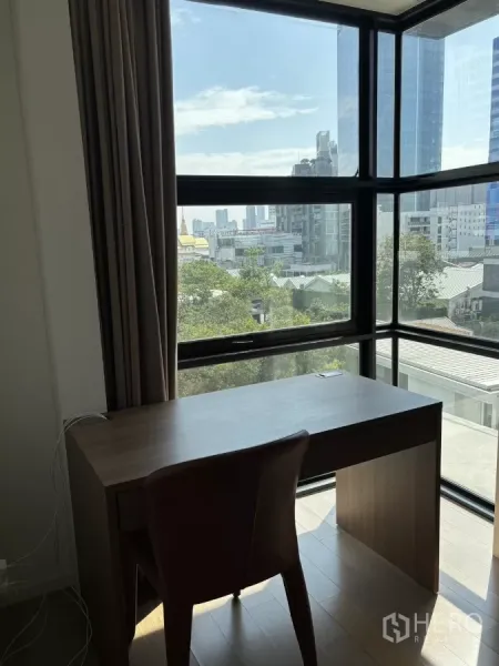 Condominium for sale in Watthana, Bangkok - Work desk beside panoramic corner window with views of Ekkamai’s cityscape.