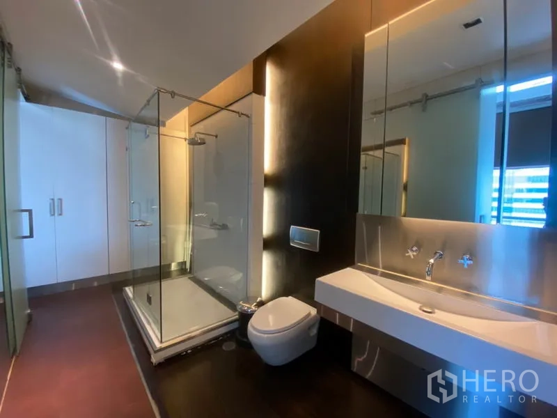 公寓 出租在Sathon, Bangkok - 卫浴间设玻璃淋浴房、挂壁式马桶与长台盆。