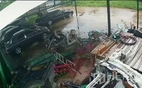Warehouse for sale in Mueang Nonthaburi, Nonthaburi - Covered work and parking area with cars and stacked industrial materials on wet concrete after rain.