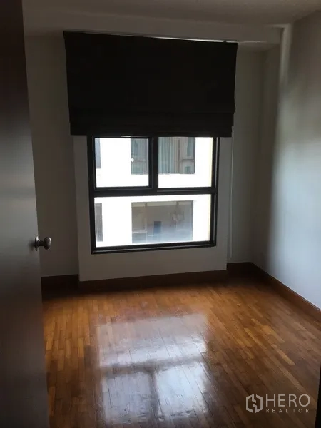 Condominium for rent in Pathum Wan, Bangkok - Compact spare room with wood flooring and a window with blackout blind.