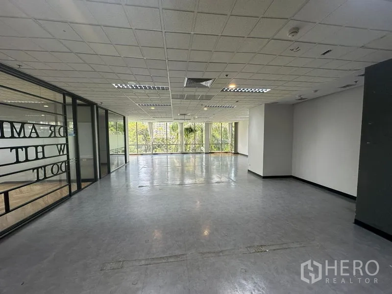 Office Space for rent - Open-plan area with glass partitions and expansive corner windows over palm trees.