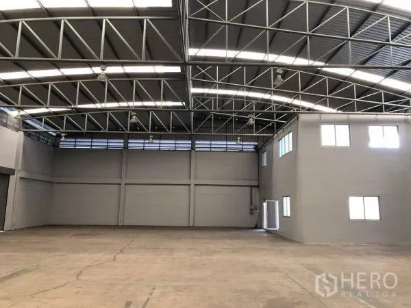 工厂 出租在Pathum Thani - 明亮仓储区，钢梁与条形天窗，开放地面适合储存或生产。