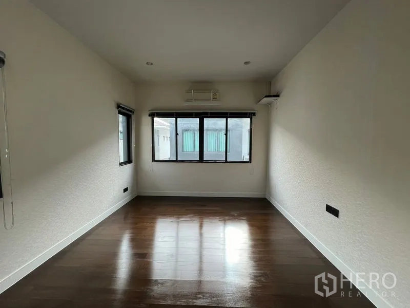 Detached House for rent in Bang Kapi, Bangkok - Empty multipurpose room with dark wooden floors and windows.