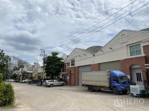 货栈 出租在Samut Sakhon - 一排仓库，停有卡车和大型卷闸门。