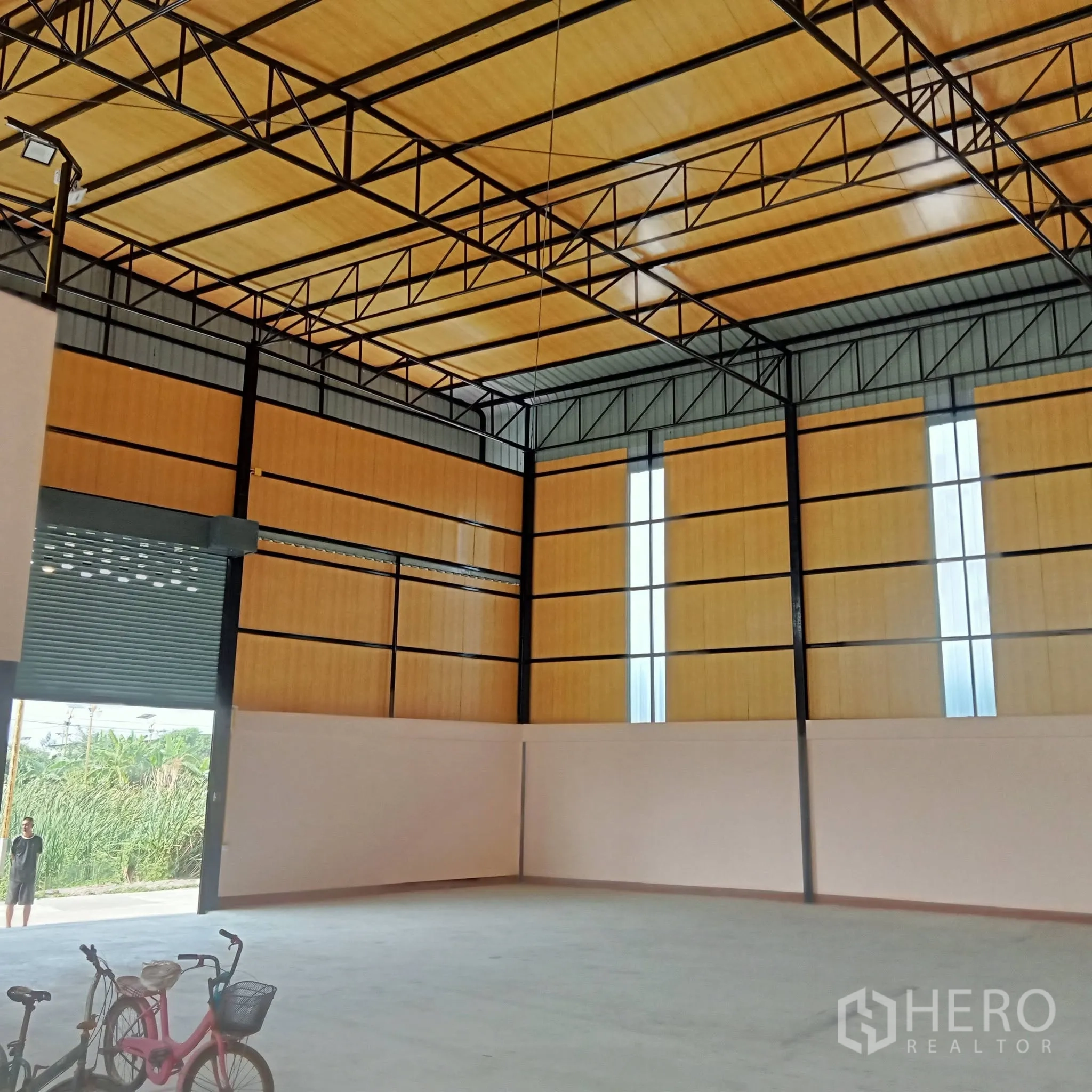 Warehouse for rent in Bang Phli, Samut Prakan - Open storage area with high roof and open roller shutter access to the outside.