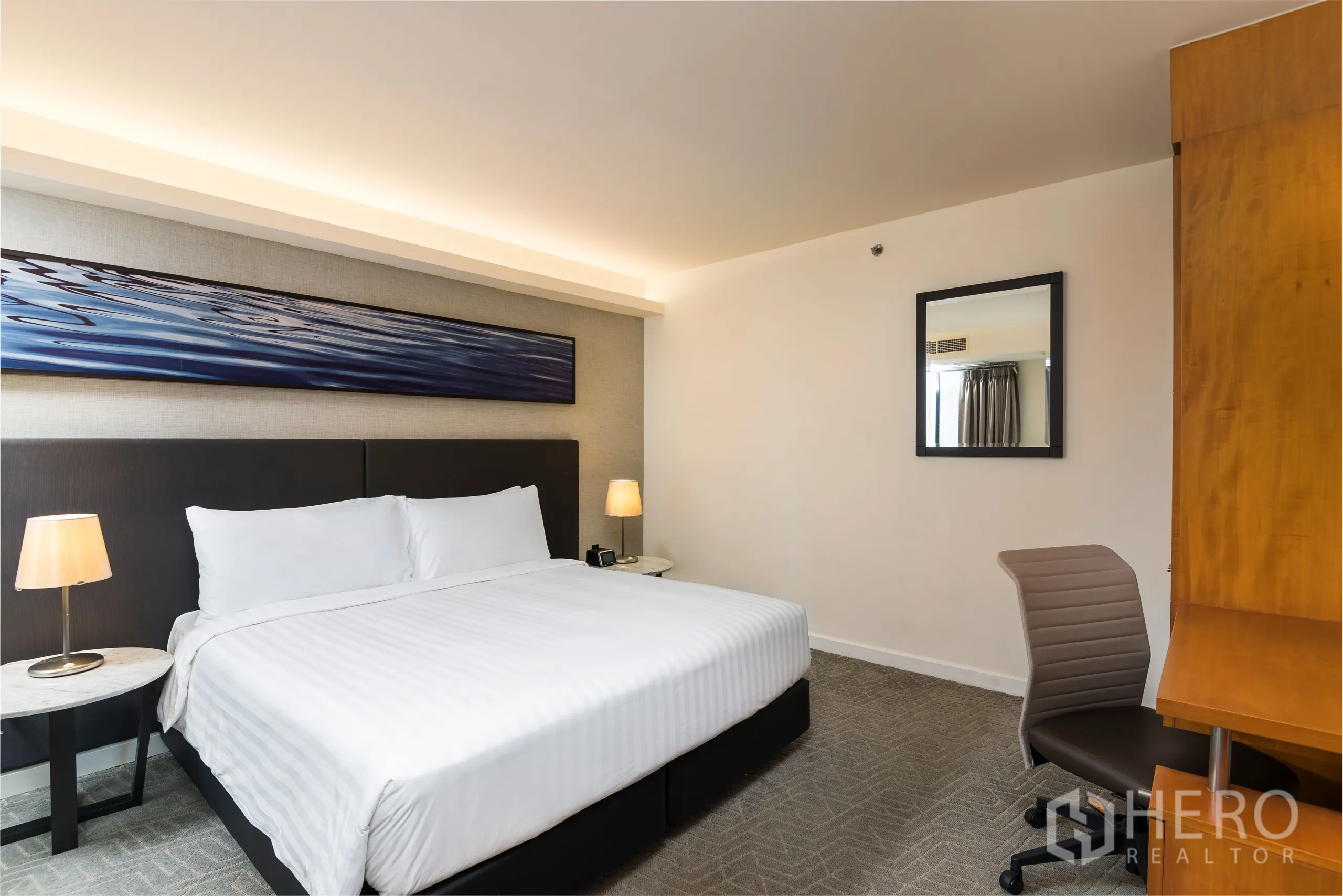 Condominium for rent in Yan Nawa, Bangkok - Spacious bedroom with king bed, desk and lamp, with a long artwork above the headboard.