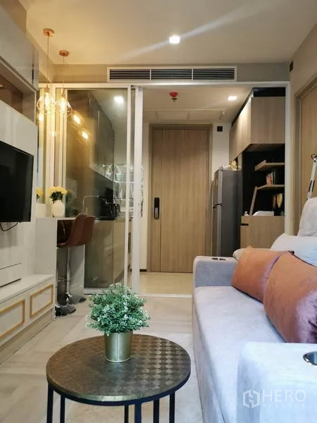 คอนโด ให้เช่าหรือขายในRatchathewi, Bangkok - ห้องนั่งเล่นมองไปยังประตูกระจกบานเลื่อนสู่ครัวย่อม พร้อมงานไม้และตู้บิลท์อิน