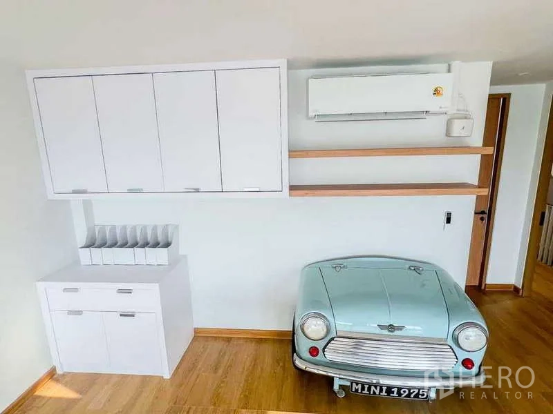 Home Office for rent in Phra Khanong, Bangkok - Alternate view of office showing Mini car decor beneath wall cabinets and an air conditioner.