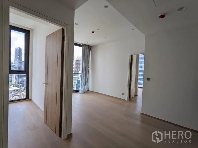 Condominium for sale - Bright corner living area with light wood floors and floor-to-ceiling windows overlooking the Silom skyline.