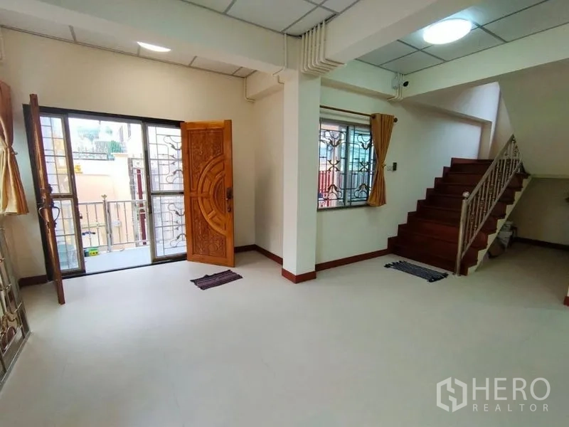 บ้าน ให้เช่าในKhlong Toei, Bangkok - โถงนั่งเล่นเชื่อมบันได ประตูไม้ และทางออกสู่ระเบียงเล็ก