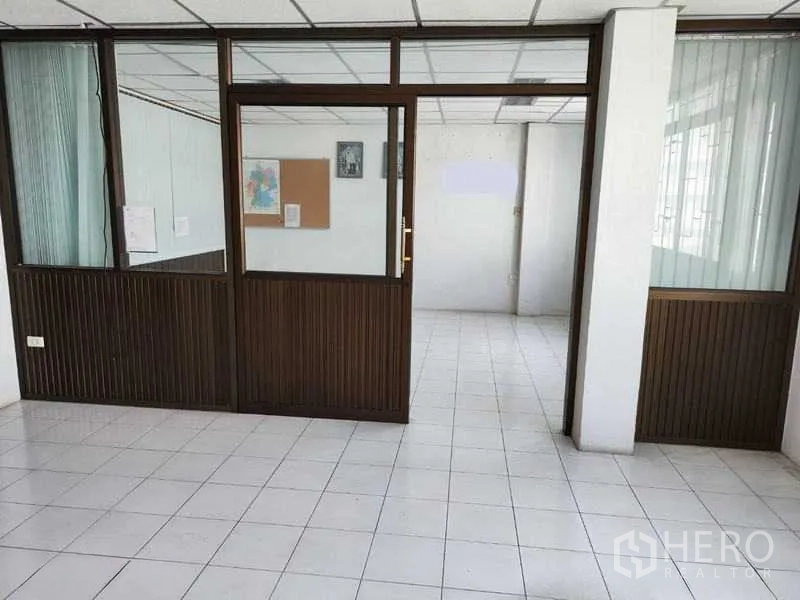 Shophouse for sale in Pathum Thani - Glass-partitioned room with door leading to office area.
