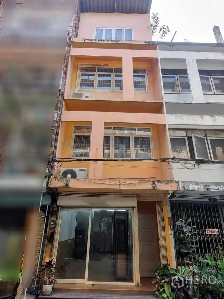ตึกแถว for rent in Phra Khanong, Bangkok - ด้านหน้าตึกอาคารพาณิชย์หลายชั้น พร้อมประตูกระจกและช่องหน้าต่าง.