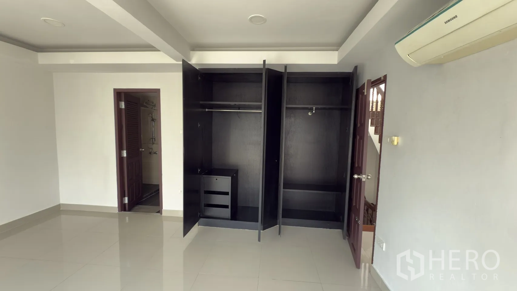 ทาวน์เฮาส์ for rent in Watthana, Bangkok - ห้องนอนกว้างมีตู้เสื้อผ้าสองตู้เปิดอยู่ พื้นเงา และประตูเข้าห้องน้ำ