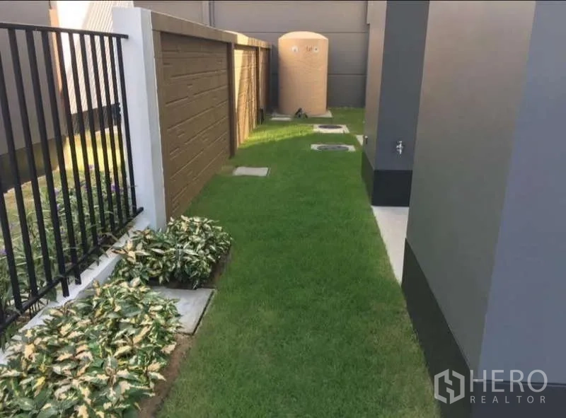 บ้าน ให้เช่าในBang Kapi, Bangkok - สวนด้านข้างทางเดินหญ้า ถังเก็บน้ำ และแปลงต้นไม้ตามแนวรั้ว