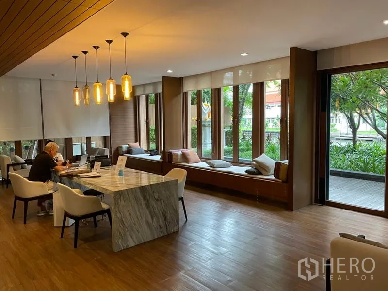 Condominium for sale in Watthana, Bangkok - Resident lounge with a marble table, pendant lights, and garden views.