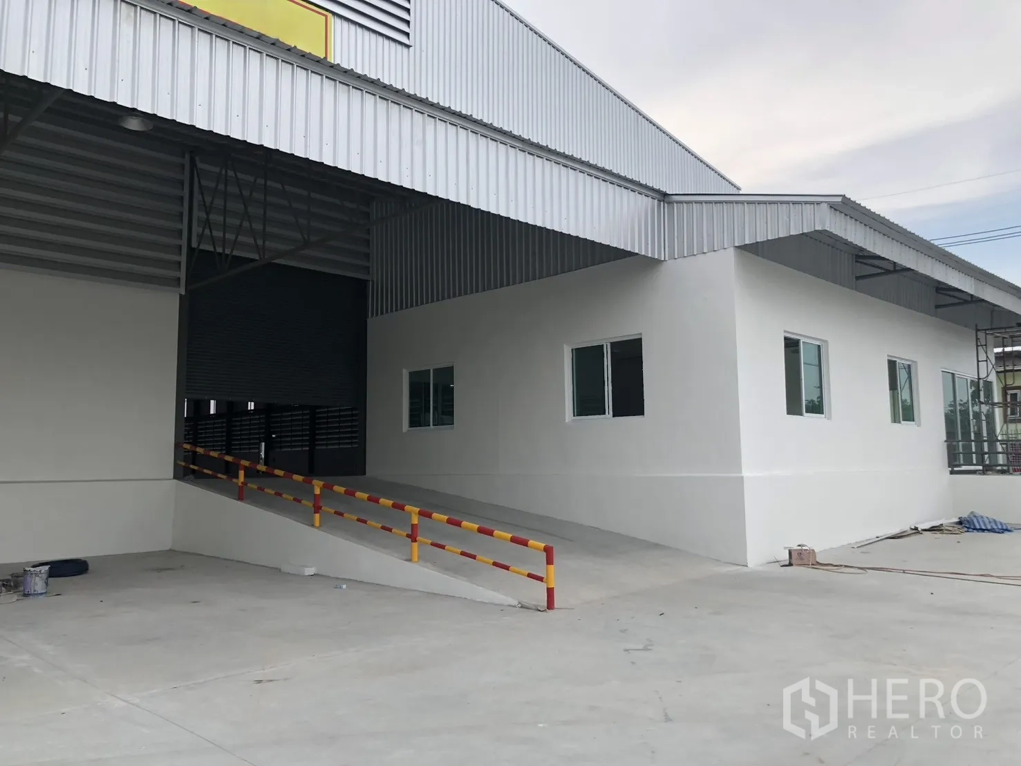 Factory for rent in Si Racha, Chon Buri - Covered loading ramp beside the office wing with windows and safety rails.