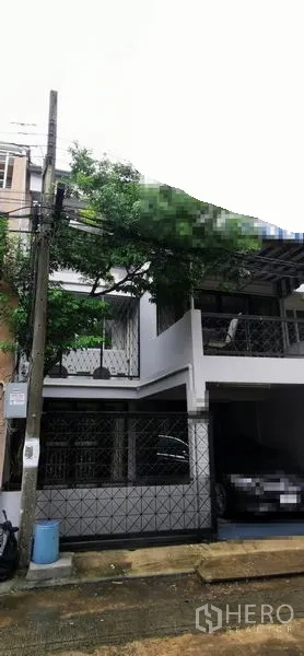 Townhouse for rent in Watthana, Bangkok - Two-storey townhouse with gated carport and leafy facade in Watthana, Bangkok