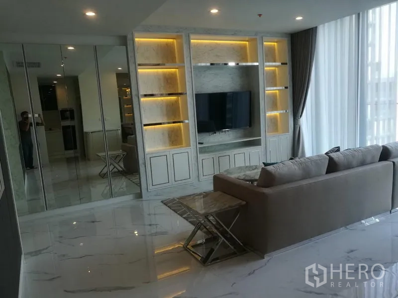 คอนโด ให้เช่าในPathum Wan, Bangkok - ห้องนั่งเล่นสว่าง มีชั้นบิลท์อินลายหินอ่อน ผนังทีวี โซฟา และผ้าม่านโปร่งสูงจรดเพดาน