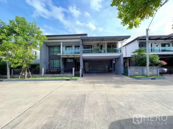 Detached House for sale in Prawet, Bangkok - Modern two-storey detached house exterior with balcony, wide carport, and gated frontage.