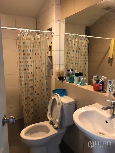 Townhouse for sale in Phasi Charoen, Bangkok - Tiled bathroom with sink, toilet, large mirror and shower with curtain.