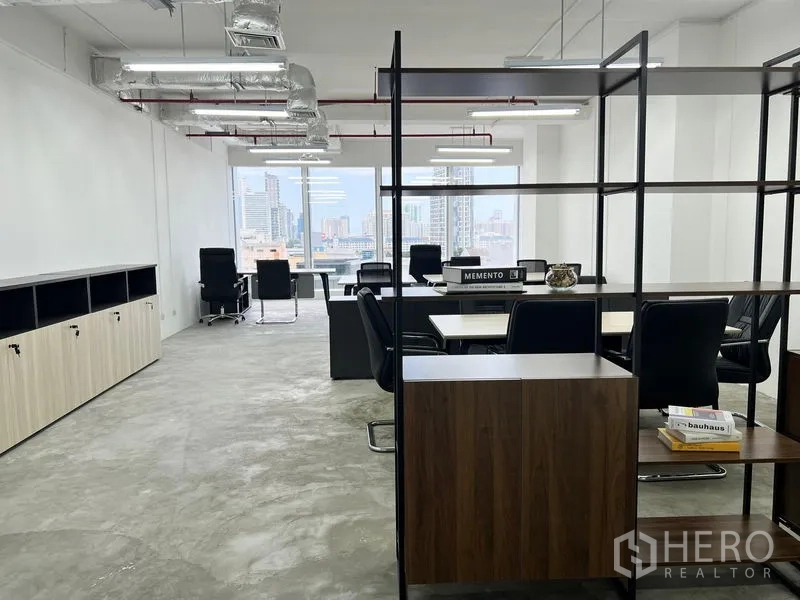 办公空间 出租在Sathon, Bangkok - 开放式布局，置物架作隔断，工位面向大窗城市景观。