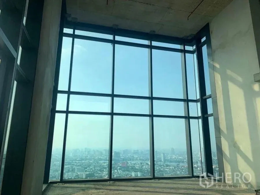 Condominium for sale in Bangkok - Corner floor-to-ceiling window offering a broad skyline view from an upper floor.