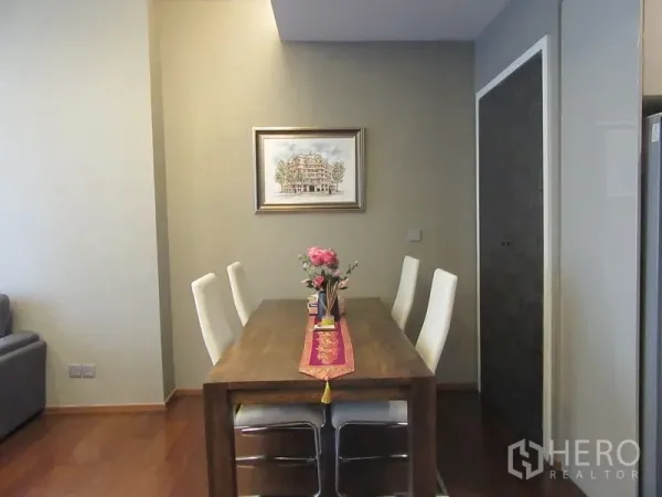 公寓 出租或出售在Watthana, Bangkok - 餐区设木质餐桌与四把白色餐椅，紧邻厨房。